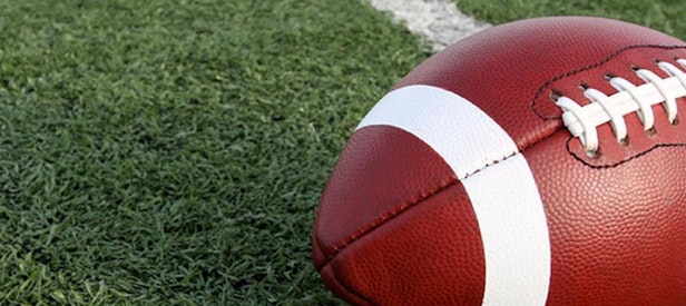 An American football on a yard line on a football field